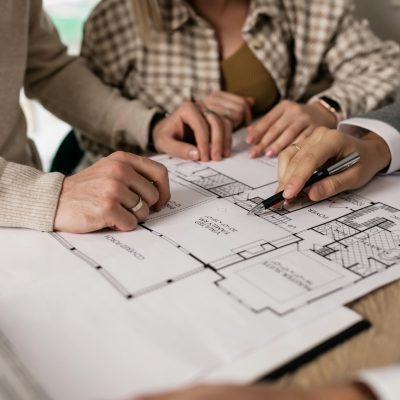 Group examining house floor plans with a real estate agent, highlighting home buying process.