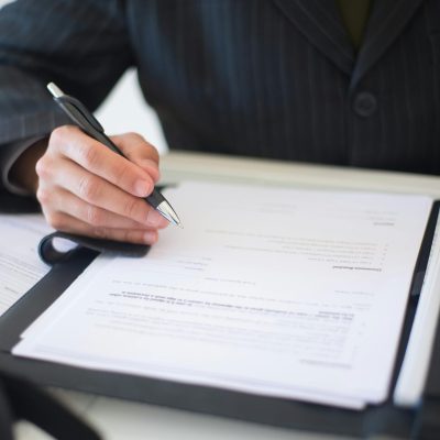 Close-up of a business professional signing documents in an office setting.